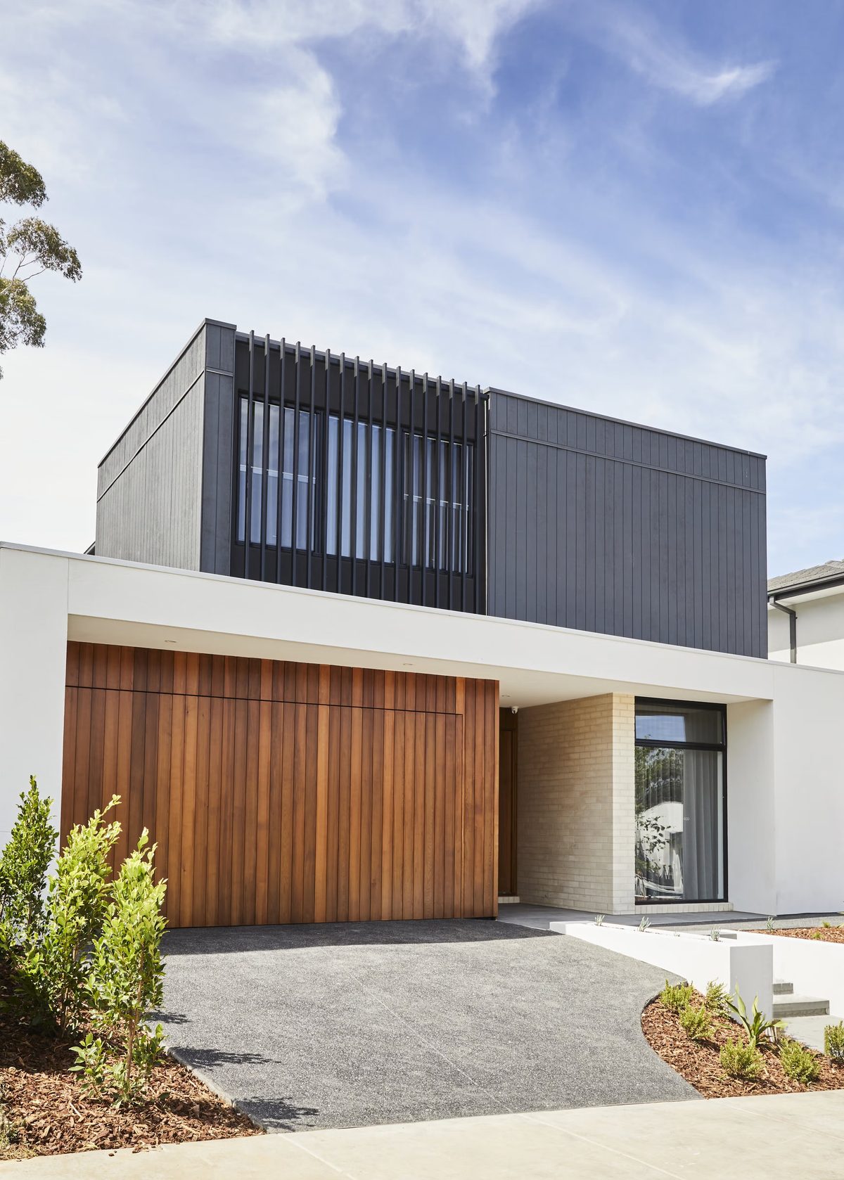 Contemporary two-storey home with a timber garage door and dark upper facade